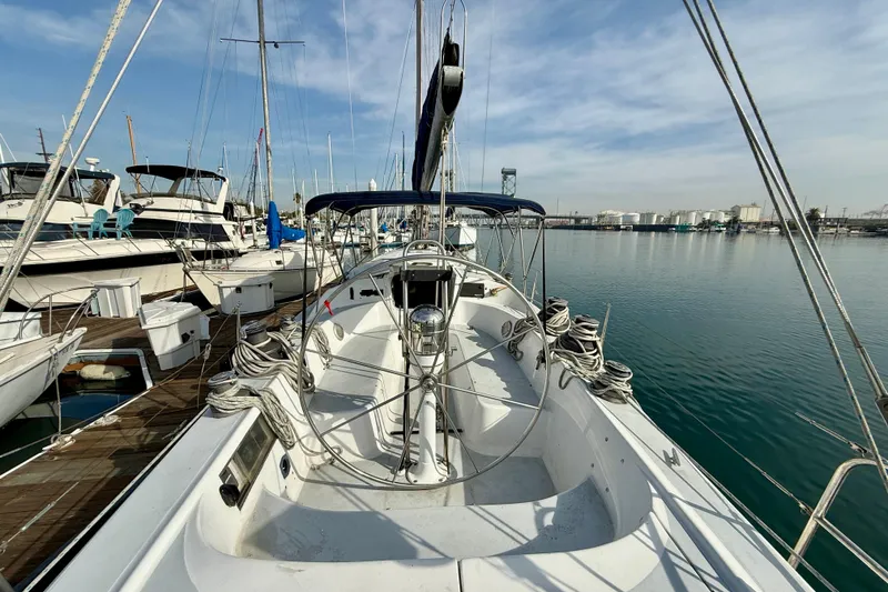 Slide: The Image of 1985 MacGregor 65 sailboat docked in a marina, surrounded by other boats. - 5