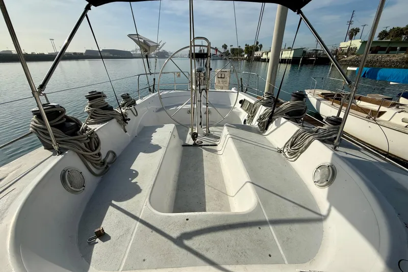 Slide: The Image of 1985 MacGregor 65 sailboat cockpit with steering wheel, docked in a marina. - 8