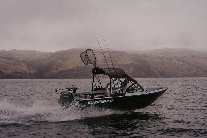 Slide: The Image of 2026 KingFisher 1625 Falcon boat cruising on a lake with scenic hills in the background. - 11