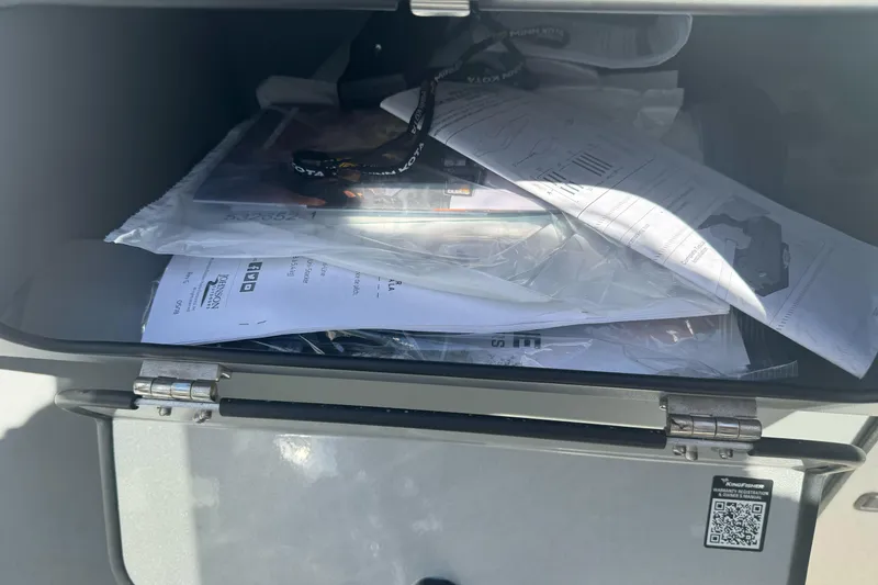 Slide: The Image of Open storage compartment with documents and lanyard in a 2026 KingFisher 16 Falcon. - 16