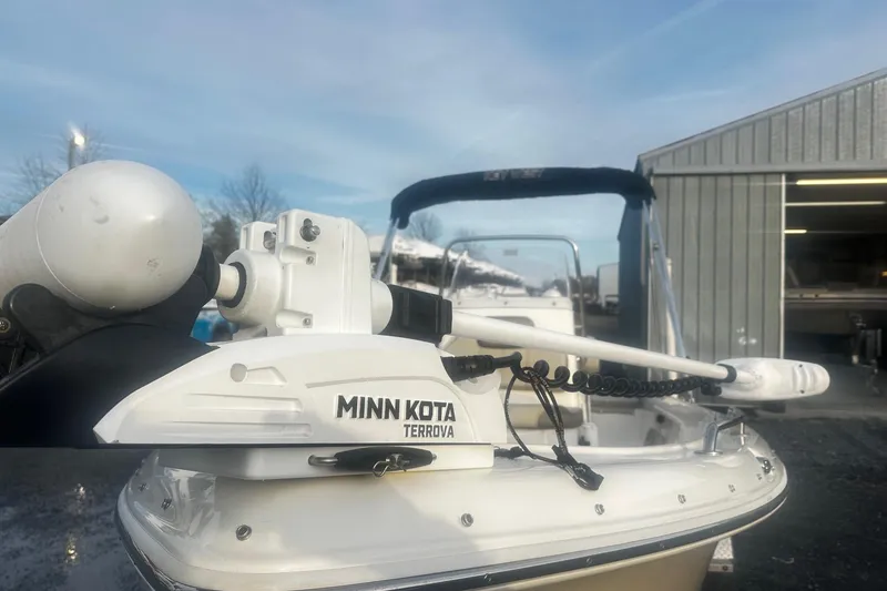 Slide: The Image of 2022 Key West 1720 Center Console boat with Minn Kota Terrova motor, parked near a metal building. - 4