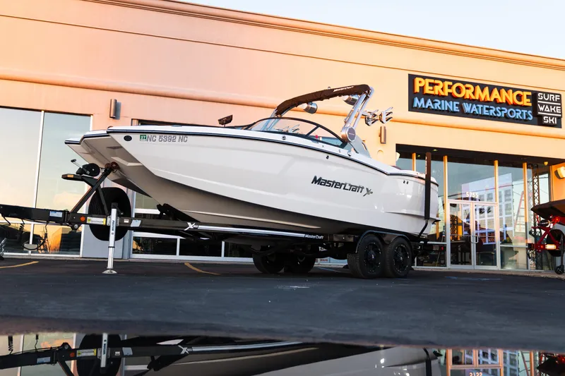 The Image of 2022 MasterCraft XStar boat on trailer outside Performance Marine Watersports store. - 1
