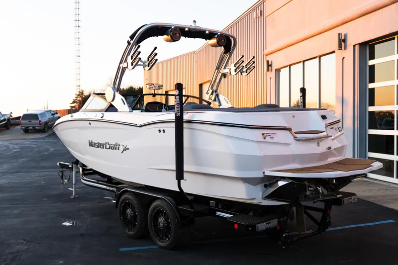 Slide: The Image of 2022 MasterCraft XStar boat on trailer, parked outside a building at sunset. - 5