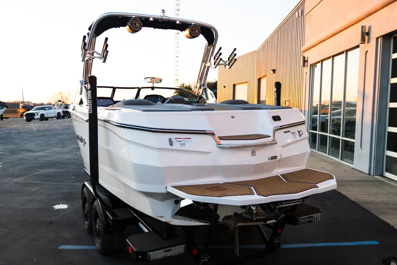 Slide: The Image of 2022 MasterCraft XStar boat on trailer outside a modern building at sunset. - 6