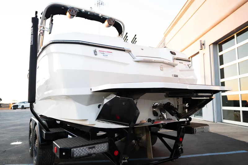 Slide: The Image of 2022 MasterCraft XStar boat on trailer, rear view, parked near a building. - 7