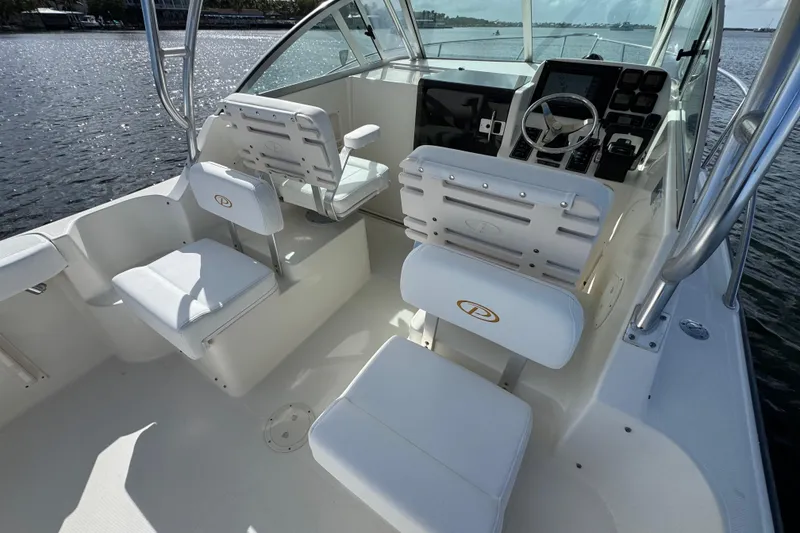 Slide: The Image of 2007 Pursuit OS 255 Offshore boat interior with white seating and steering console. - 11