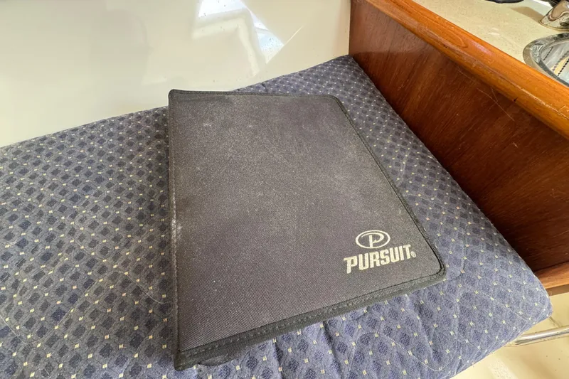 Slide: The Image of Black Pursuit folder on patterned seat inside 2007 OS 255 Offshore boat. - 14