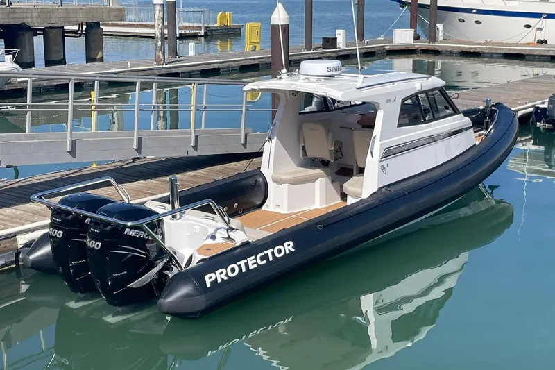 Slide: The Image of 2024 Protector 330 Targa boat with twin 400 HP engines docked at marina. - 2