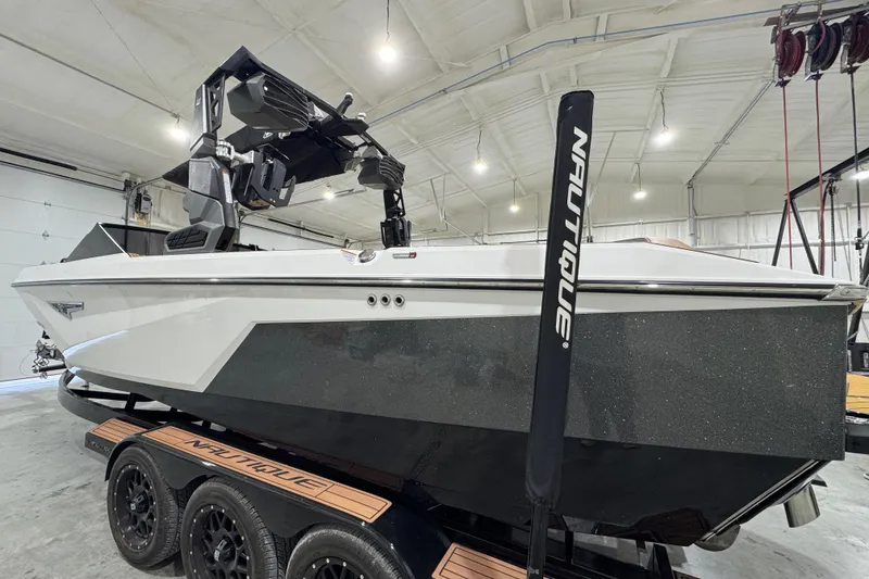 The Image of 2023 Nautique Super Air Nautique S25 boat on trailer in showroom. - 2