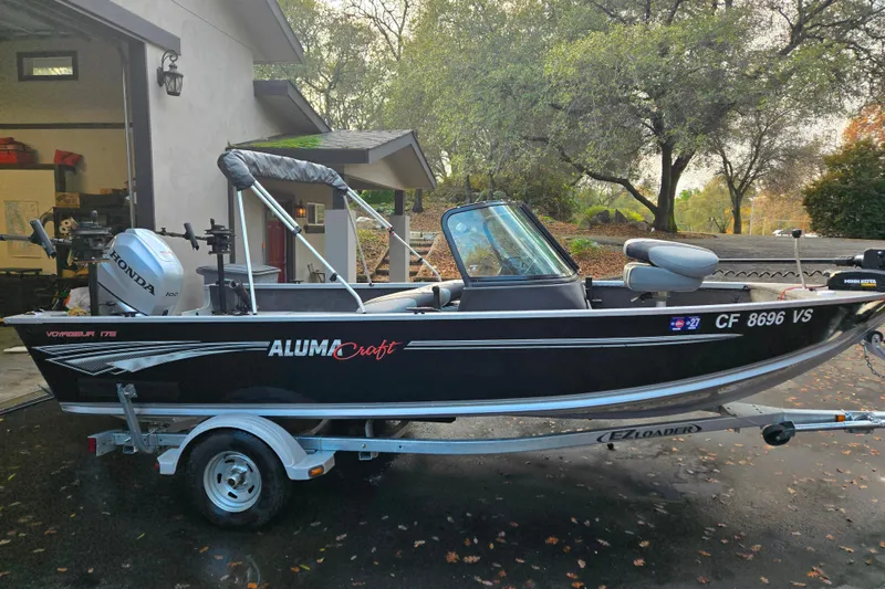Slide: The Image of 2020 Alumacraft Voyageur 175 Sport boat on trailer, parked near a garage. - 11