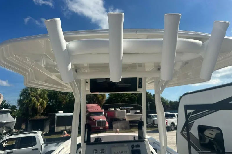 Slide: The Image of 2024 Bayliner Trophy T24CC boat with rod holders and console, under a clear blue sky. - 15