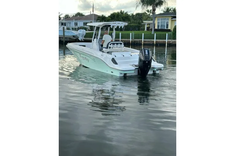 Slide: The Image of 2024 Bayliner Trophy T24CC boat cruising on calm water near a residential dock. - 21
