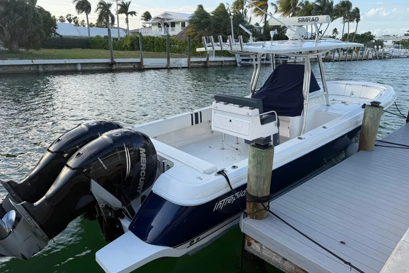 The Image of 2013 Intrepid 327 Cuddy boat docked, featuring dual Mercury engines and sleek design. - 1
