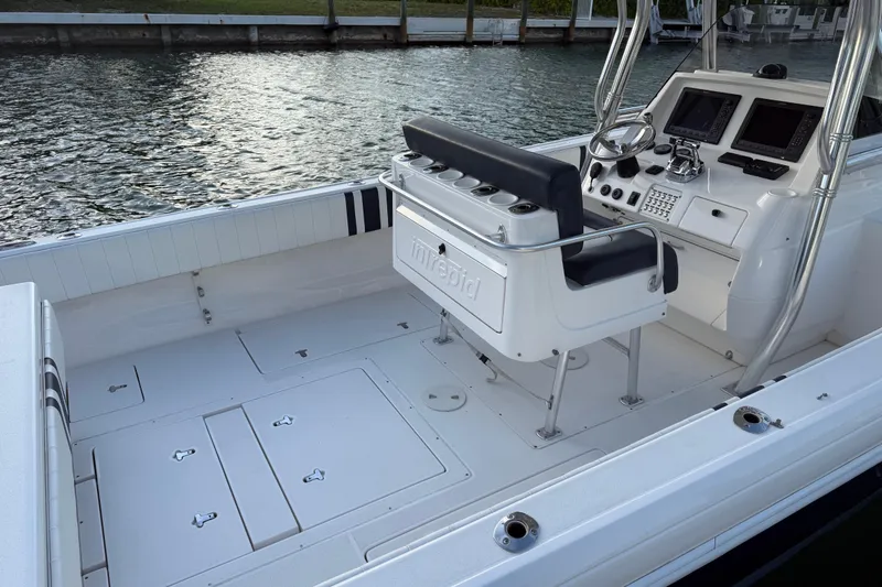 Slide: The Image of 2013 Intrepid 327 Cuddy boat interior with helm and seating, docked by the water. - 5