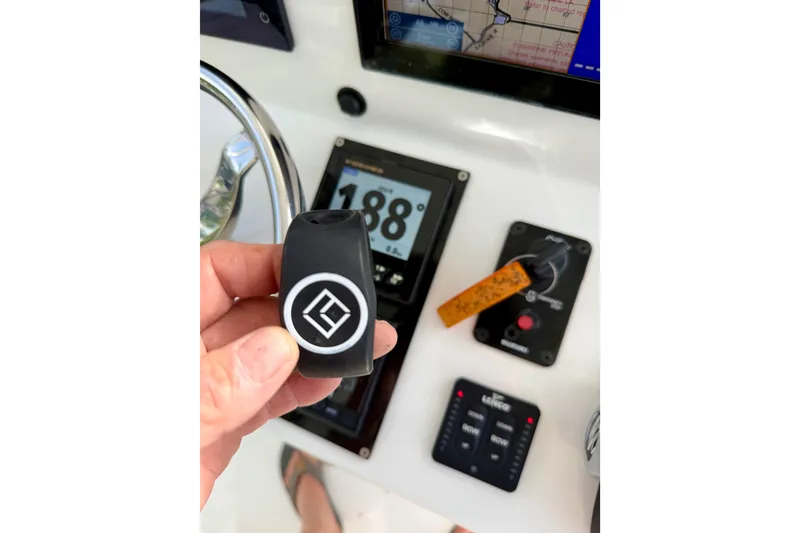 Slide: The Image of Hand holding a key fob on a 2025 Ocean Master 296 Center Console dashboard. - 10