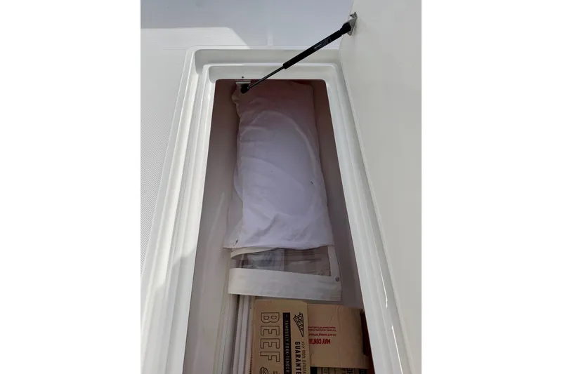 Slide: The Image of Storage compartment in 2025 Ocean Master 296 Center Console boat, containing wrapped items and boxes. - 7