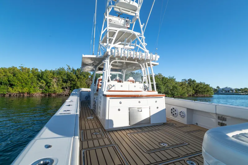 Slide: The Image of 2018 HCB 53 Suenos RXV boat on water, featuring spacious deck and clear blue sky. - 21
