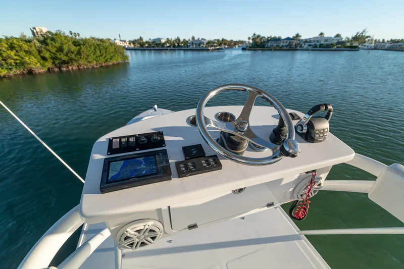 Slide: The Image of 2018 HCB 53 Suenos RXV boat helm with navigation controls on calm water. - 56