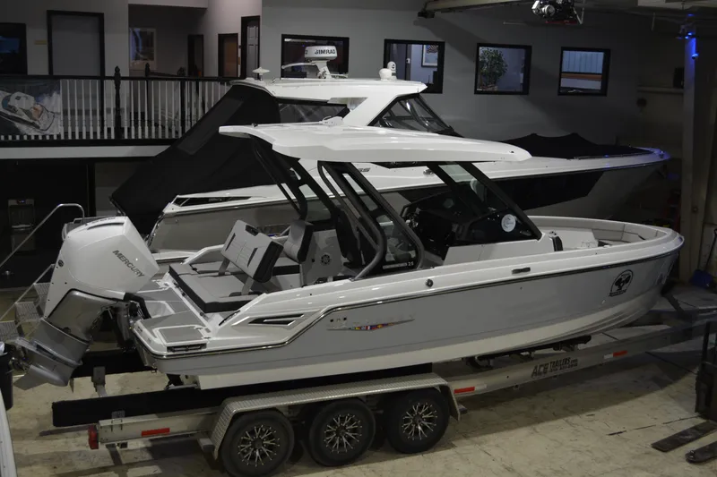 Slide: The Image of 2026 Monterey Elite 25 OB boat on trailer in showroom, featuring sleek design and Mercury outboard engine. - 3