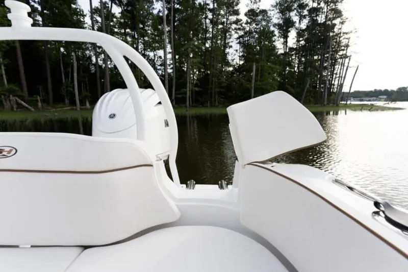Slide: The Image of Manufacturer Provided Image: 2026 Sea Hunt Ultra 239 SE boat interior with white seating, near a serene lake and trees. - 9