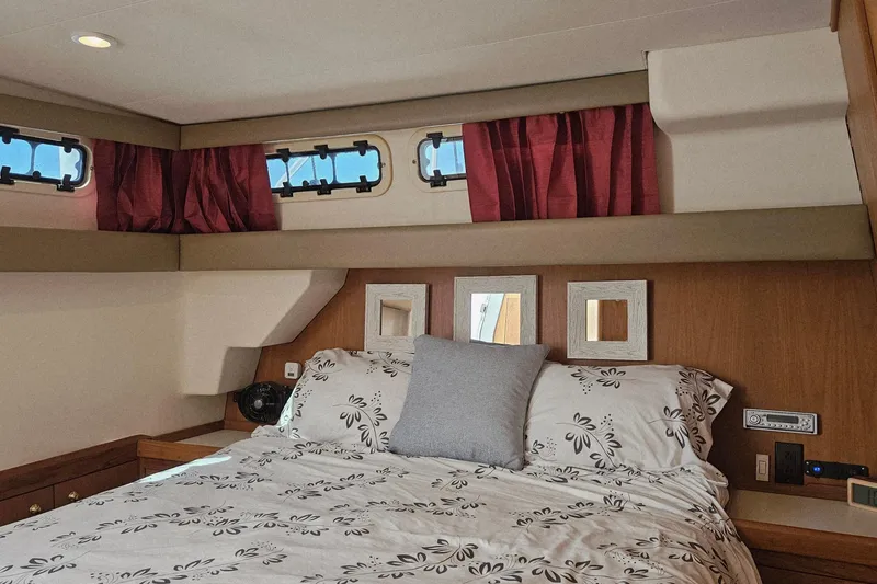 Slide: The Image of Cozy bedroom interior of 1999 Mainship 430 Trawler with floral bedding and red curtains. - 11