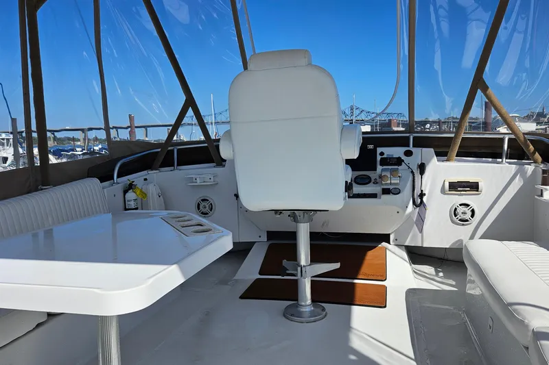 Slide: The Image of 1999 Mainship 430 Trawler helm with white seating, table, and navigation controls. - 3