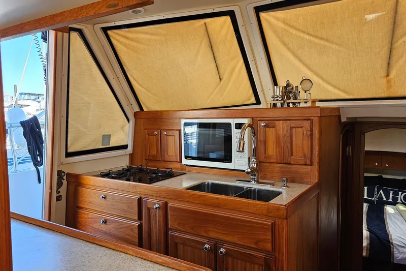 Slide: The Image of 1999 Mainship 430 Trawler kitchen with wooden cabinetry, stove, and microwave. - 8