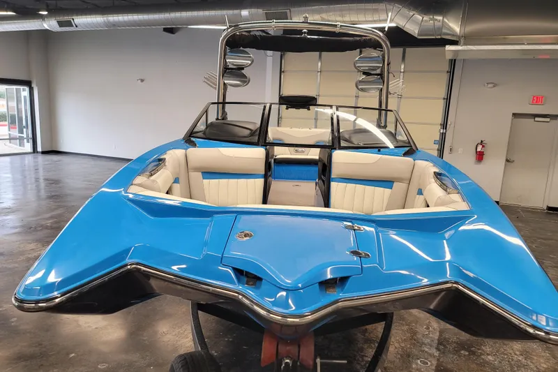Slide: The Image of 2014 Malibu Wakesetter 24 MXZ boat with blue exterior in a showroom. - 2