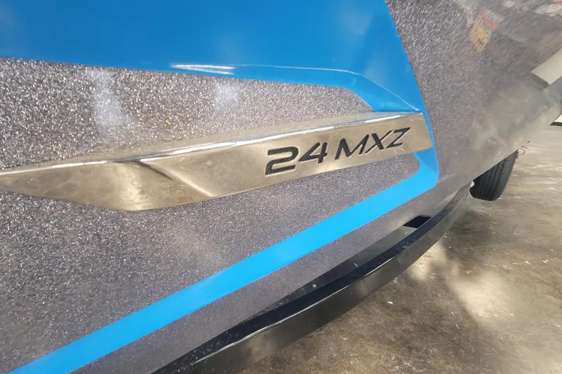 Slide: The Image of 2014 Malibu Wakesetter 24 MXZ boat emblem on a metallic blue surface. - 25
