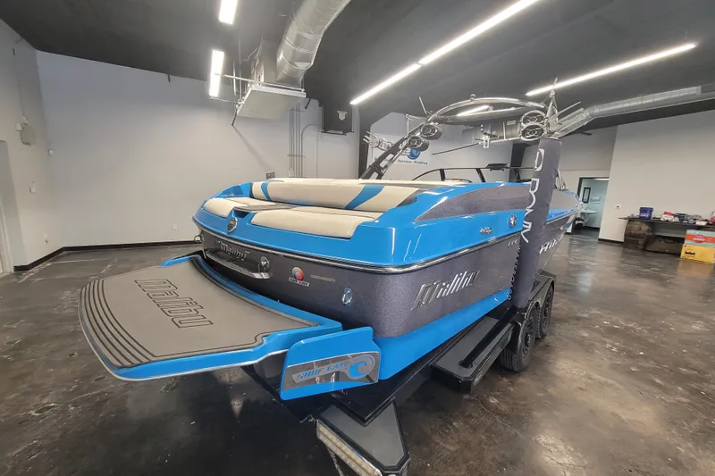 Slide: The Image of 2014 Malibu Wakesetter 24 MXZ boat in a showroom, featuring a sleek blue design. - 26