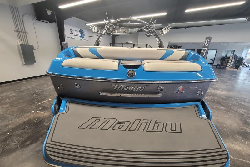 Slide: The Image of 2014 Malibu Wakesetter 24 MXZ boat in showroom, rear view with blue and gray accents. - 27