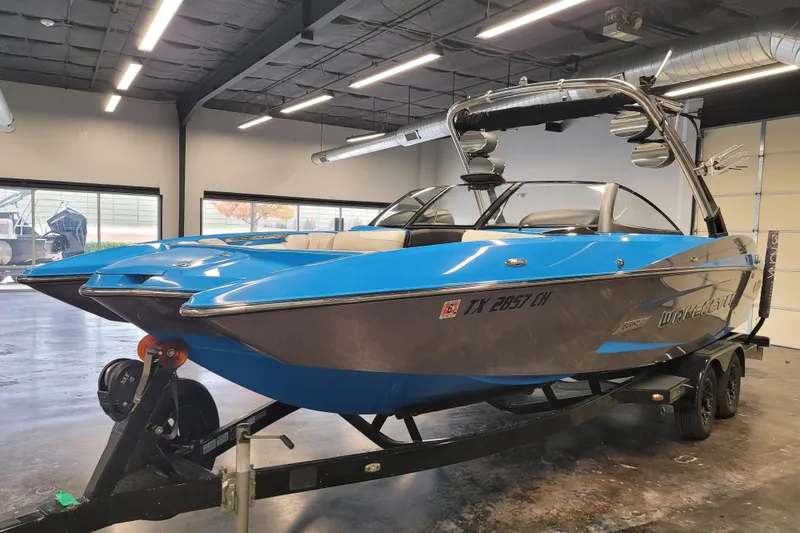 Slide: The Image of 2014 Malibu Wakesetter 24 MXZ boat in showroom, blue and gray exterior, on trailer. - 4
