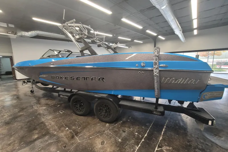 Slide: The Image of 2014 Malibu Wakesetter 24 MXZ boat in showroom, blue and gray design on trailer. - 6