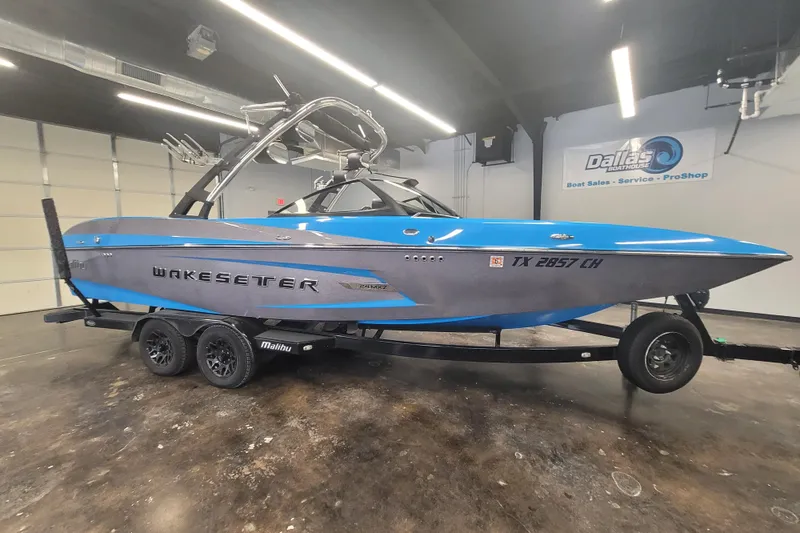 Slide: The Image of 2014 Malibu Wakesetter 24 MXZ boat in showroom, blue and gray design. - 7