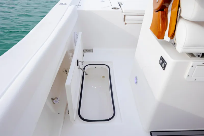 Slide: The Image of 2026 Caymas 291 boat interior with open storage compartment, white seating, and ocean view. - 36