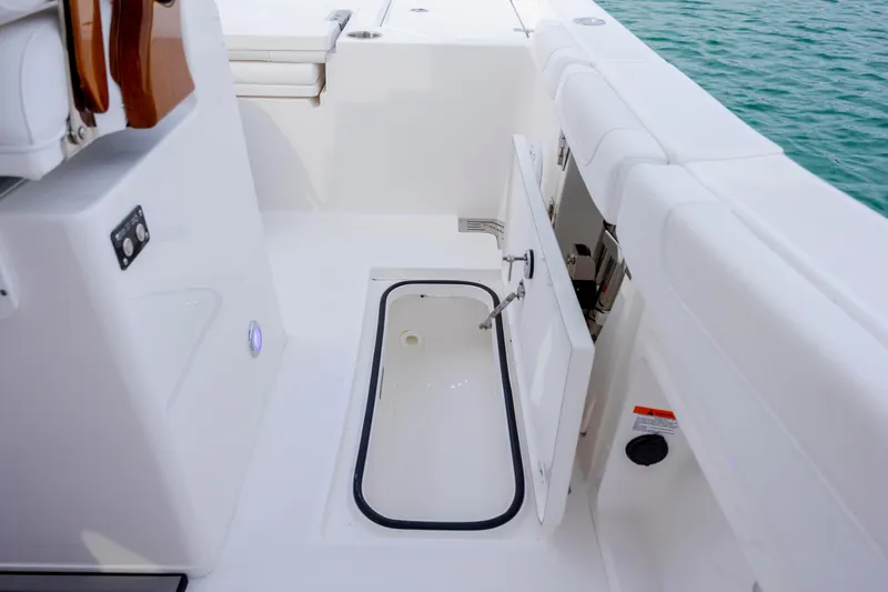 Slide: The Image of 2026 Caymas 291 boat interior with open storage compartment, white seating, and ocean view. - 37