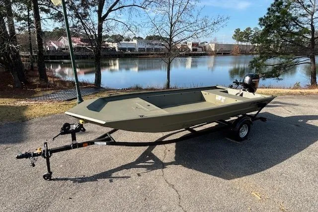 The Image of 2026 Tracker Grizzly 1860 Utility boat on trailer by a scenic lake. - 0