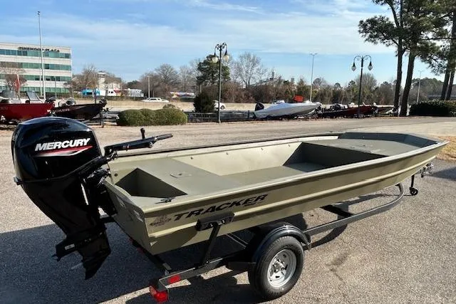 Slide: The Image of 2026 Tracker Grizzly 1860 Utility boat with Mercury engine on trailer, parked outdoors. - 3