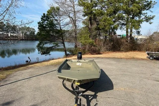 Slide: The Image of 2026 Tracker Grizzly 1860 Utility boat on trailer by a scenic lake. - 5