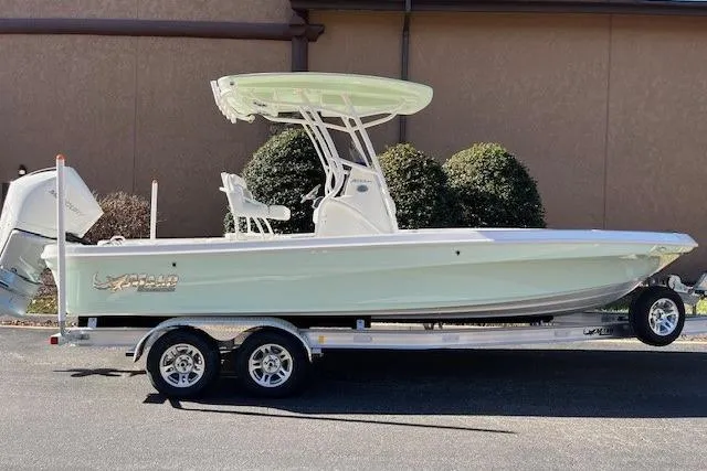 The Image of 2026 Mako 24 APEX boat on trailer, side view, light green hull, outdoor setting. - 0
