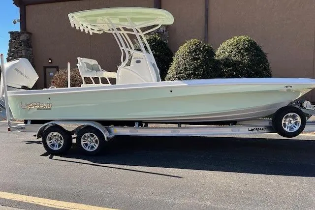 Slide: The Image of 2026 Mako 24 APEX boat on trailer, parked outdoors, side view. - 1