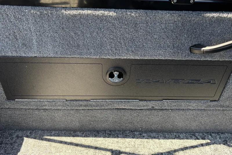 Slide: The Image of 2026 Tracker Targa V-18 Combo storage compartment with lock, featuring carpeted interior. - 52