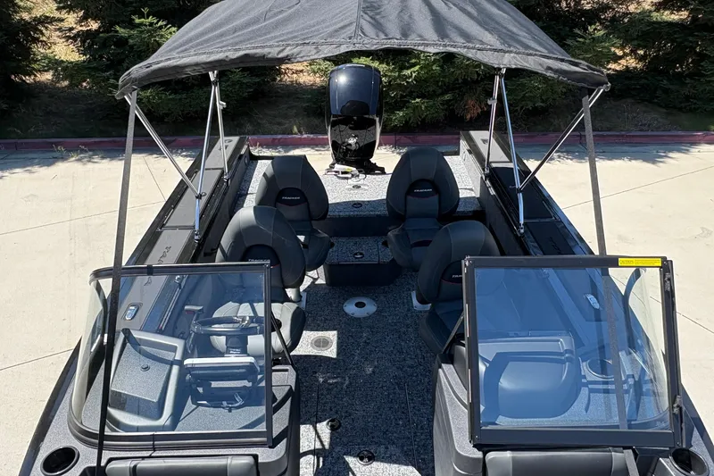 Slide: The Image of 2026 Tracker Targa V-18 Combo boat with canopy, seating, and windshield, parked outdoors. - 30