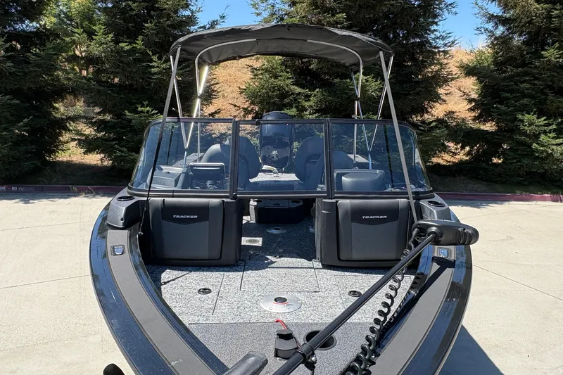 Slide: The Image of 2026 Tracker Targa V-18 Combo boat with canopy, parked outdoors near trees. - 10