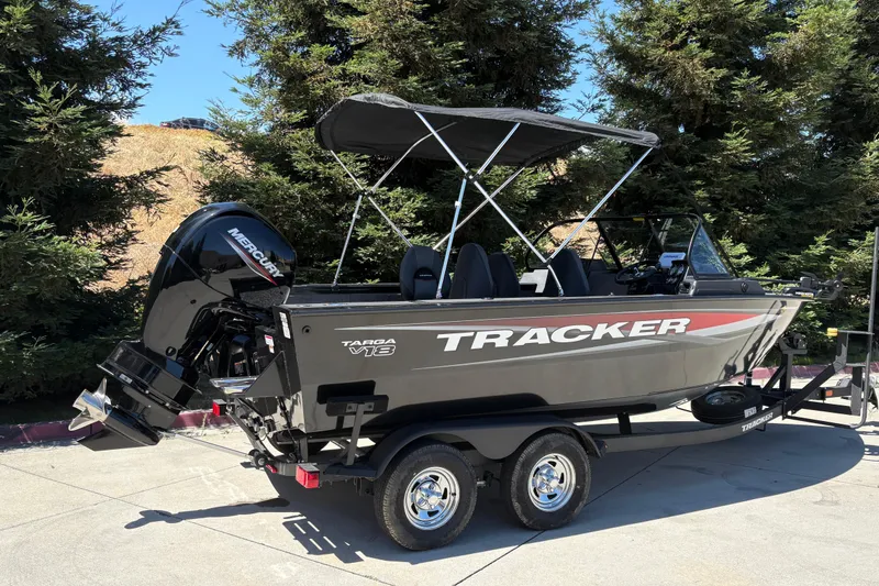 Slide: The Image of 2026 Tracker Targa V-18 Combo boat with Mercury engine on trailer, parked outdoors. - 6