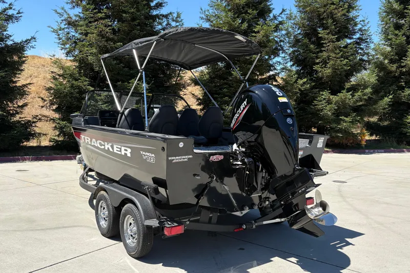 Slide: The Image of 2026 Tracker Targa V-18 Combo boat with Mercury engine on trailer, parked outdoors. - 7