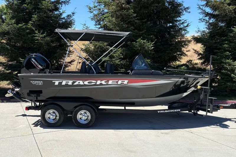 The Image of 2026 Tracker Targa V-18 Combo boat on trailer, parked outdoors with trees in background. - 0