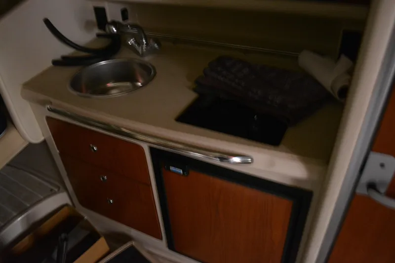 Slide: The Image of 2004 Chaparral Signature 290 boat kitchenette with sink and storage cabinets. - 32