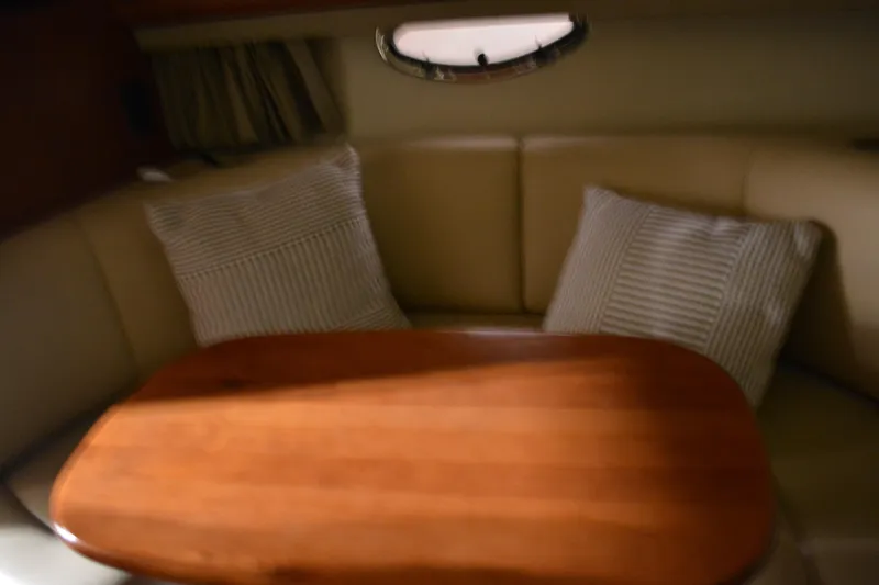 Slide: The Image of 2004 Chaparral Signature 290 cabin interior with wooden table and cushioned seating. - 34
