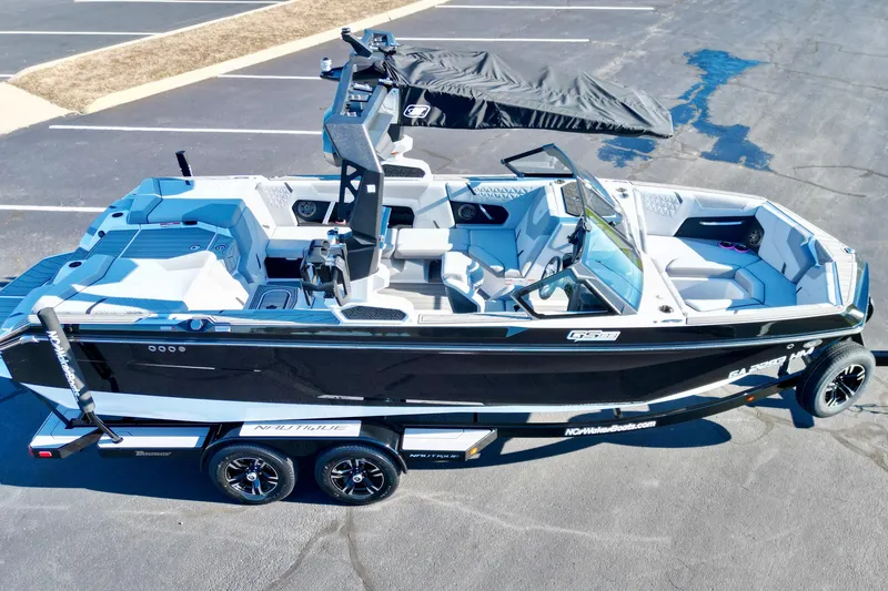 Slide: The Image of 2023 Nautique Super Air Nautique GS22 boat on trailer, black and white design, parked on asphalt. - 6